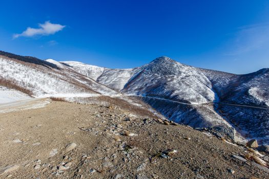 Road mountain serpentine among the high snow-capped mountains