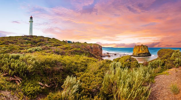 Vivid and dramatic sunset over panorama of a famous Split Point Lighthouse and Eagle Rock in the sea. Aireys Inlet at Great Ocean Road on southern coast of Victoria state, Australia. 