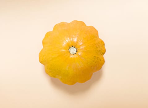 Pumpkin in the middle of beige background. Simple flat lay.