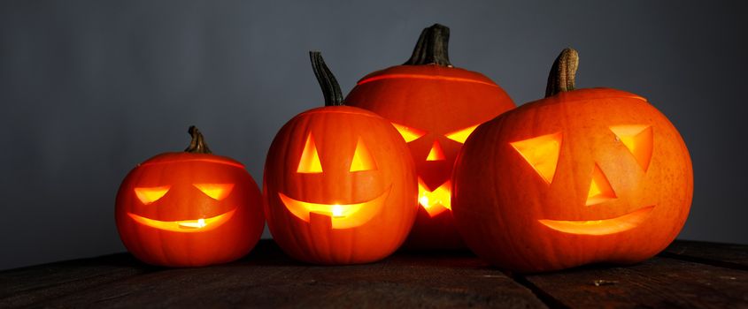 Halloween pumpkin head lanterns and burning candles on wooden background