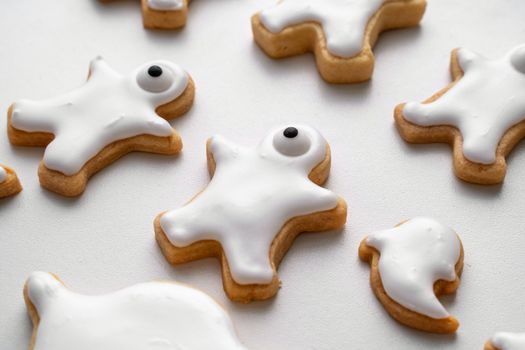 Close up of decorating cute Halloween gingerbread cookies with frosting icing cream topping bag.