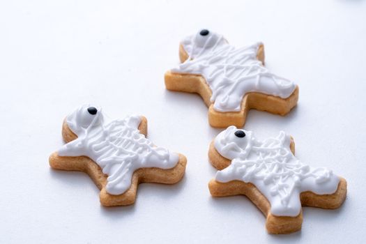 Close up of decorating cute Halloween gingerbread cookies with frosting icing cream topping bag.