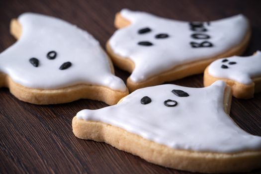 Close up of decorating cute Halloween ghost gingerbread cookies with frosting icing cream topping bag.