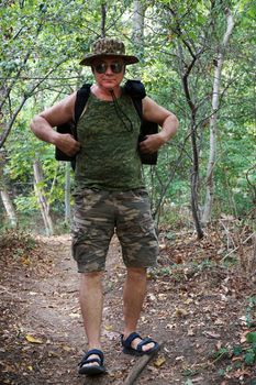 a man with a backpack walks along a path in the forest.