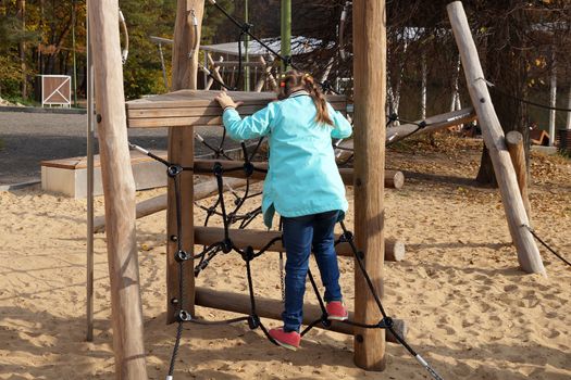 child girl climbing rope playground in the park.