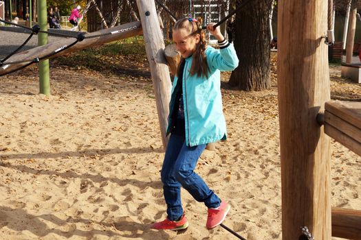 child girl walks the tightrope on the rope playground in the park