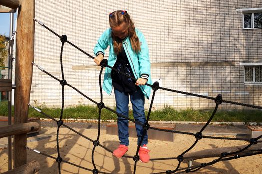 little girl climbing rope ladder on the playground in the park