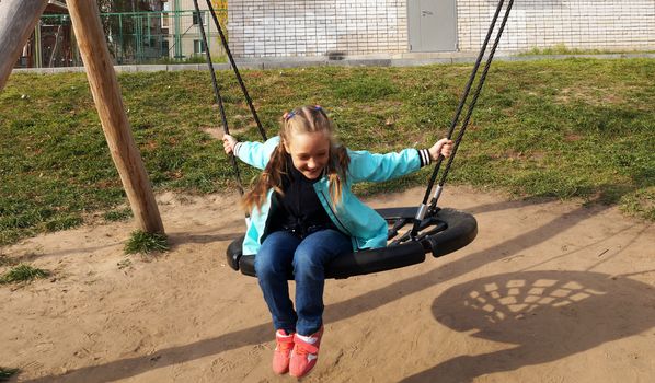 Little girl riding a swing and laughing in the park