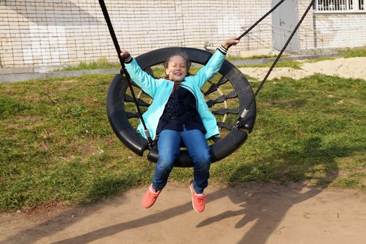 Little girl riding a swing and laughing in the park