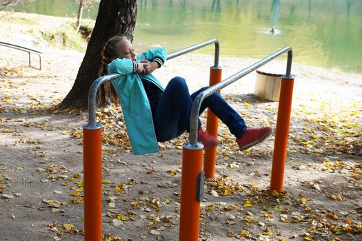 child girl is engaged on the sportground in the park.