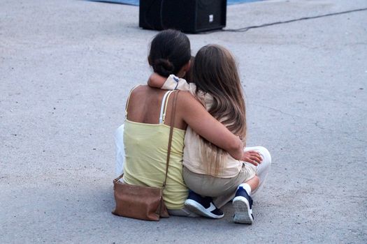 Varna, Bulgaria - 13, September, 2020: mom and daughter are hugging on the pavement, rear view