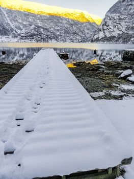 Snow-covered jetty in a winter landscape at the fjord lake in Framfjorden, Vestland, Vik, Norway.