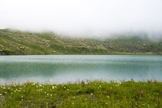 Mountain lake and fog, misty lake, amazing landscape and view of alpine lake Okhrotskhali in the Svaneti, Georgia