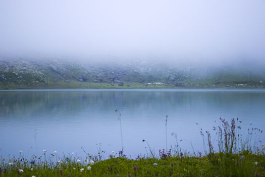 Mountain lake and fog, misty lake, amazing landscape and view of alpine lake Okhrotskhali in the Svaneti, Georgia
