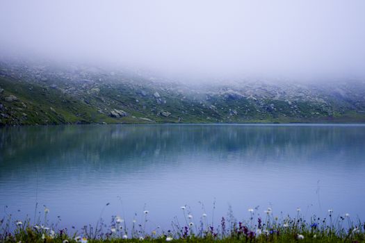 Mountain lake and fog, misty lake, amazing landscape and view of alpine lake Okhrotskhali in the Svaneti, Georgia