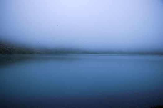 Mountain lake and fog, misty lake, amazing landscape and view of alpine lake Okhrotskhali in the Svaneti, Georgia