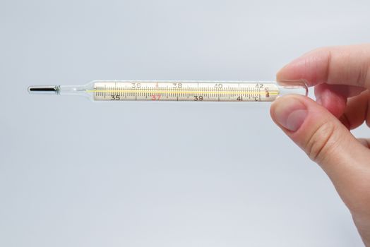 mercury thermometer in the man's hand isolated on a blue background. Temperature measurement using a thermometer. High fever and illness. Close up