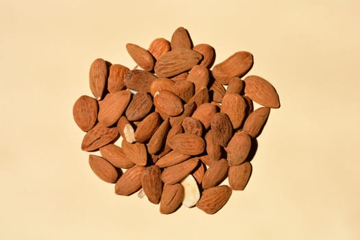 Raw almonds on light yellow background