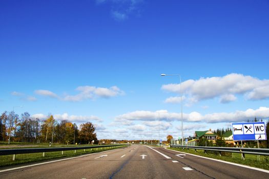 Highway landscape in Europe, street and sings on the road.Blue sky and daylight, green trees and buildings.