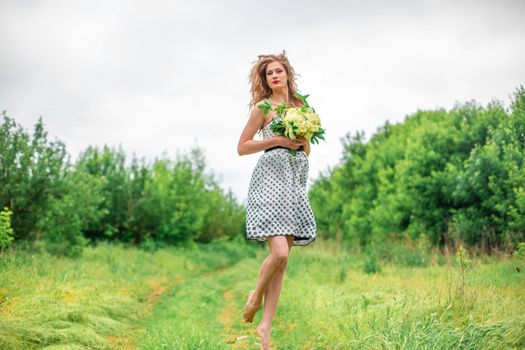 A beautiful young blonde girl collected a bouquet of wildflowers. Enjoy a walk on a warm summer day.