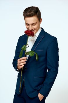 A man in a suit with a rose in his hands a gift date light background. High quality photo