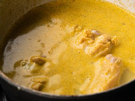 Close-up Cooking of Chicken Green Curry, adding Fresh Green Thai Eggplant, Chili and Basil into boiling curry in pan. Local Thai food.