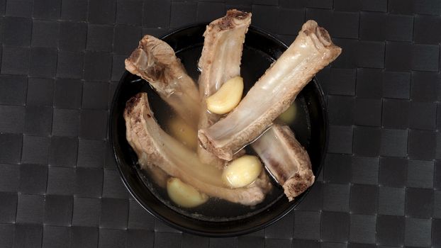 Bak kut teh or pork ribs soup which made from many ingredients such as big garlic, white pepper and many spices. Very popular traditional authentic menu dish in Singapore and Malaysia. Served hot with rice bowl