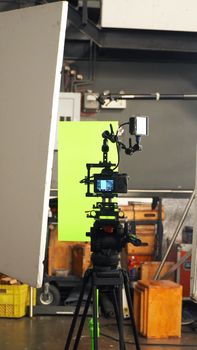 Behind video camera and green screen for movie or film production and equipment in the big studio.