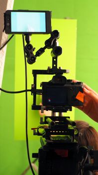 Behind video camera and green screen for movie or film production and equipment in the big studio.