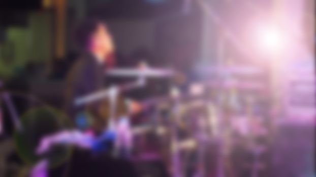 Blurry image of musician performing live show concert on the stage with professional equipment.