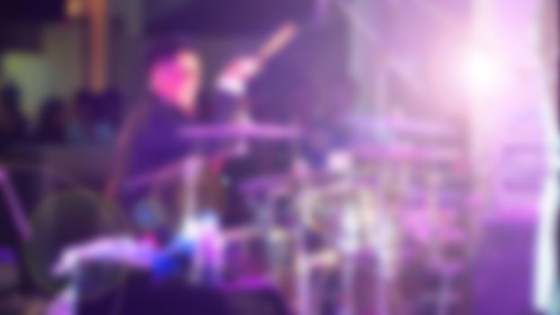 Blurry image of musician performing live show concert on the stage with professional equipment.