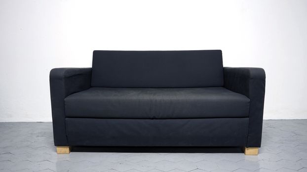 Black color sofa that made from wood and fabric in the white room and grey floor and no people.