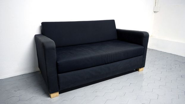 Black color sofa that made from wood and fabric in the white room and grey floor and no people.