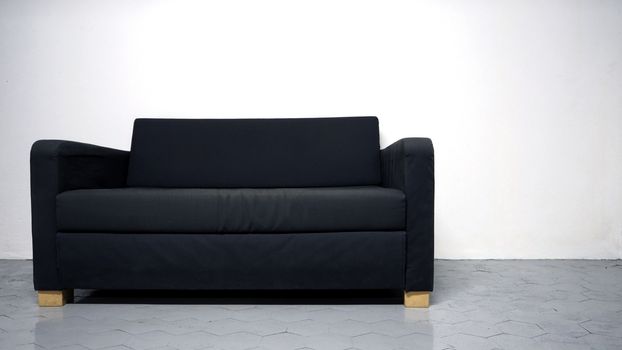 Black color sofa that made from wood and fabric in the white room and grey floor and no people.