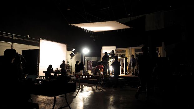 Behind the scenes of video shooting production crew team silhouette and camera equipment in studio. 