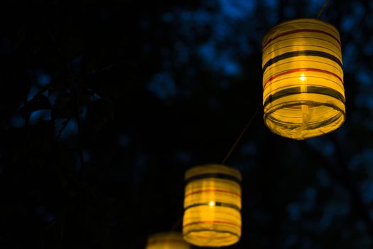 Lantern in the yard, night and warm light, hanging lanterns, natural light, evening time.