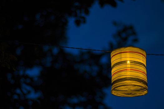 Lantern in the yard, night and warm light, hanging lanterns, natural light, evening time.