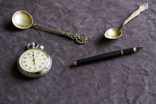 Vintage pocket clock, fountain pen and spoons on the table