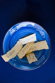 Tasty, delicious, dinner time letters and text, empty blue tableware, bowl and plate on the blue table. Dish set. Table setting.