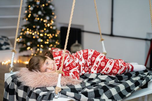 A little girl in pajamas can't sleep on a festive night. Christmas magic fairy tale. Happy childhood.