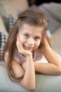 Portrait of a little girl who lies on the sofa, leaning on her arm.