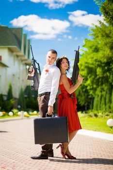 Young couple of criminals with weapons and a suitcase full of money.