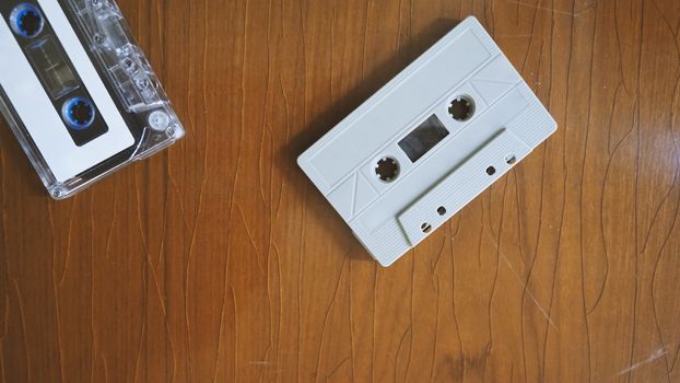 Close-up images of cassette tape on retro wood table. represent nostalgia mood or moment to 80s or 90s that most of audio music or songs recorded in compact and handy device technology.