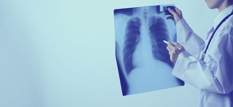 Middle aged of asian woman doctor standing and holding a x-ray film or radiography. she looking for unnormal or disease on lungs which illness from coronavirus pandemic