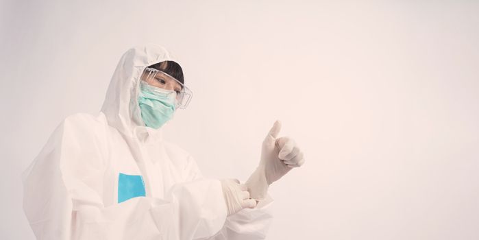 Asia woman doctor in PPE suit or Personal Protective Equipment uniform and wearing medical face mask, rubber gloves and goggles for protect coronavirus pandemic. Studio shot with copy space.
