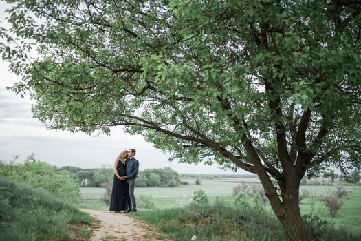 A loving couple walks in the field, the girl is pregnant. Walk in the fresh air. Love and care.