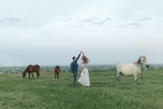 Rural couple on a green meadow communicates with animals. Pregnant wife. Therapy and relaxation for pregnant women.