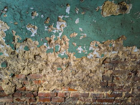 heavy damaged green painted plaster and bricks wall background and texture.