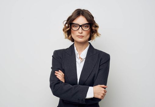 A business woman in glasses and in a suit on a light background crossed her arms over her chest. High quality photo