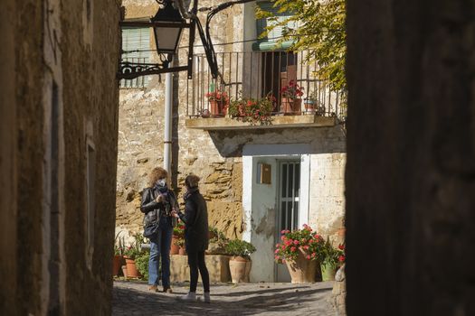 Ores, Aragon, Spain - October 12, 2020: A couple of women, neighbors, chat in one of the streets of the small town of Ores, Aragon, Spain.